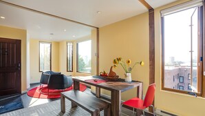 Ein moderner Essbereich mit einem Holztisch, roten Stühlen und einer Vase mit Sonnenblumen.
