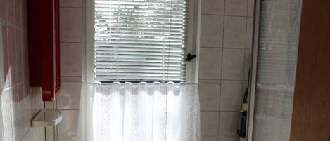 A compact bathroom with a white sink, toilet, and a window with blinds.