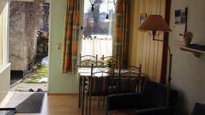 Een eethoek met een tafel en stoelen, een lamp en uitzicht door een raam met gordijnen.