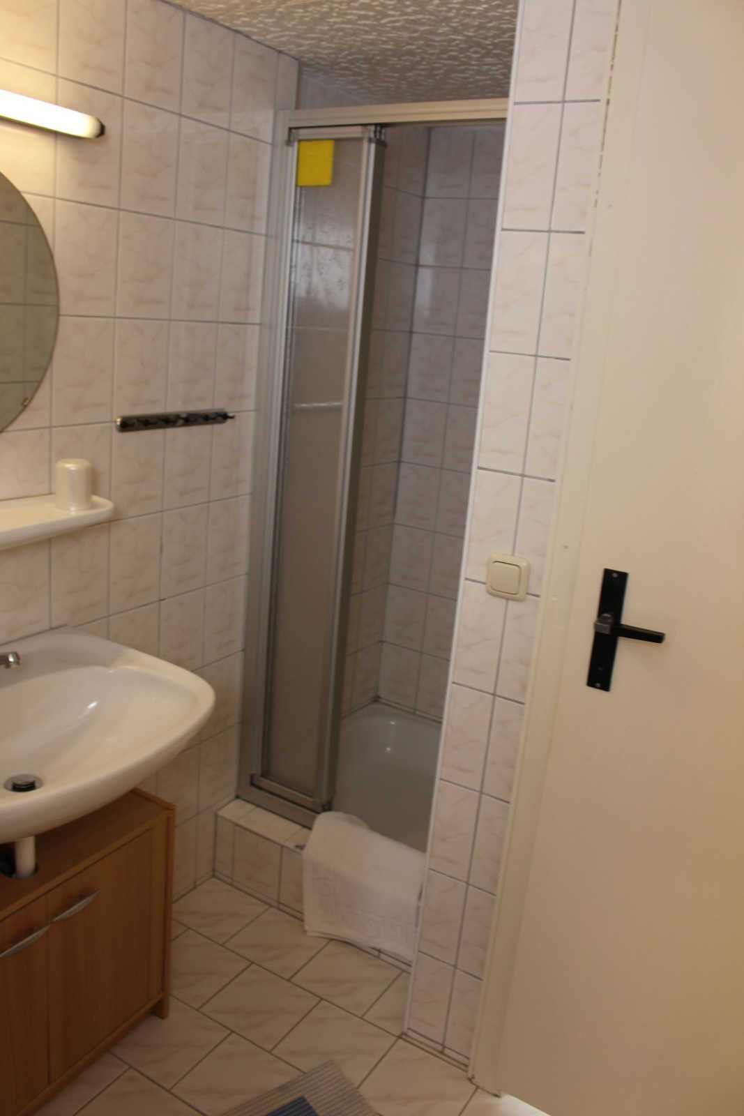 Een badkamer met wastafel, spiegel en douche.