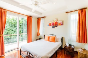 Une chambre à coucher avec un lit, une table de chevet, un ventilateur de plafond et une fenêtre avec des rideaux.