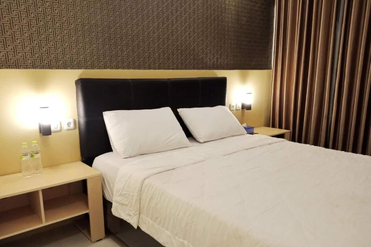 A hotel room with a bed, two bedside tables, and a nightstand.