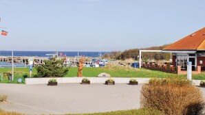 Une vue sur la côte, avec un port de plaisance, une statue et un bâtiment doté d’un toit rouge.