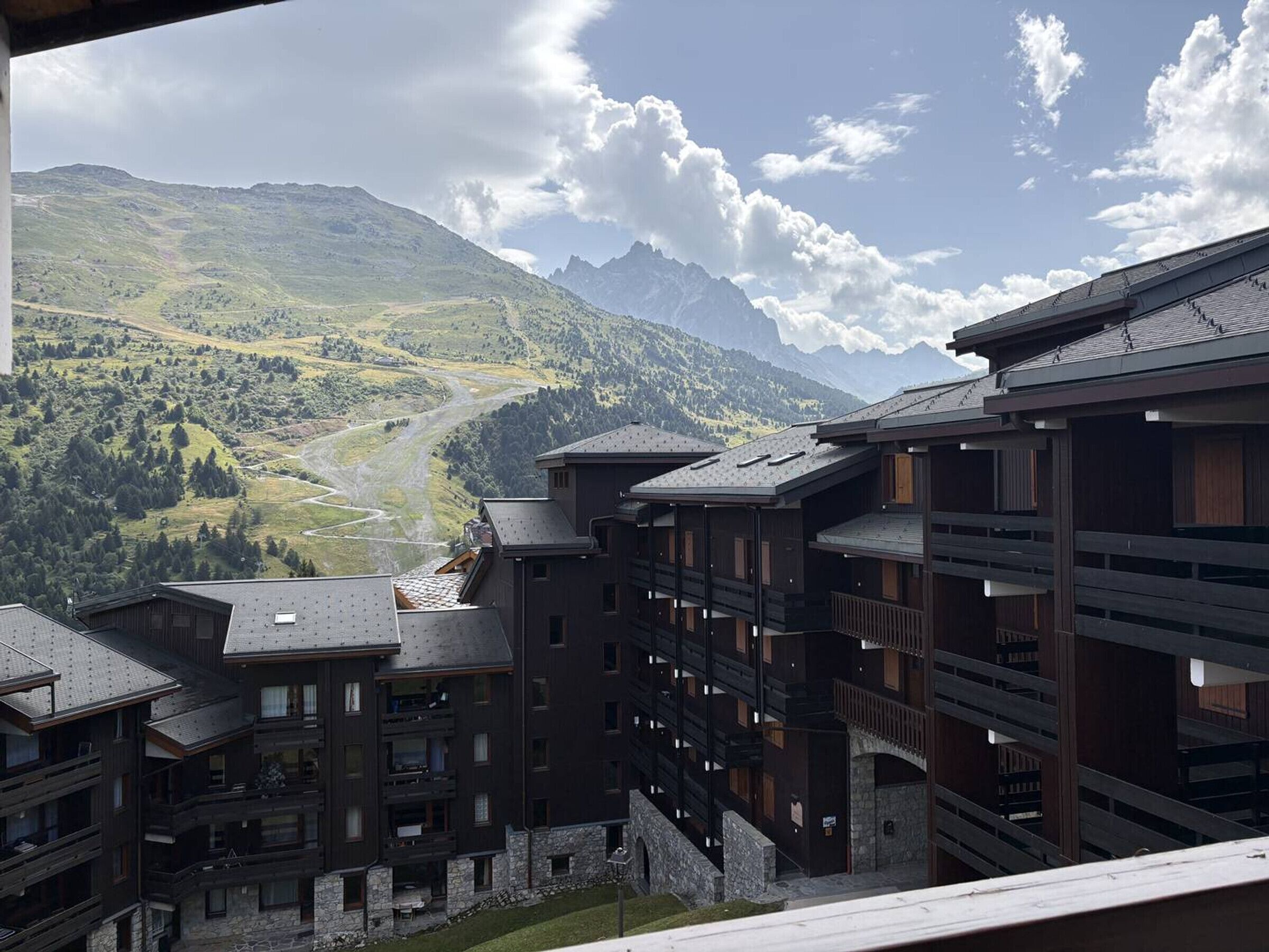 Un edificio a più piani con balconi, sullo sfondo di montagne.