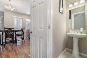 Bathroom features a pedestal sink, large mirror, and chandelier.