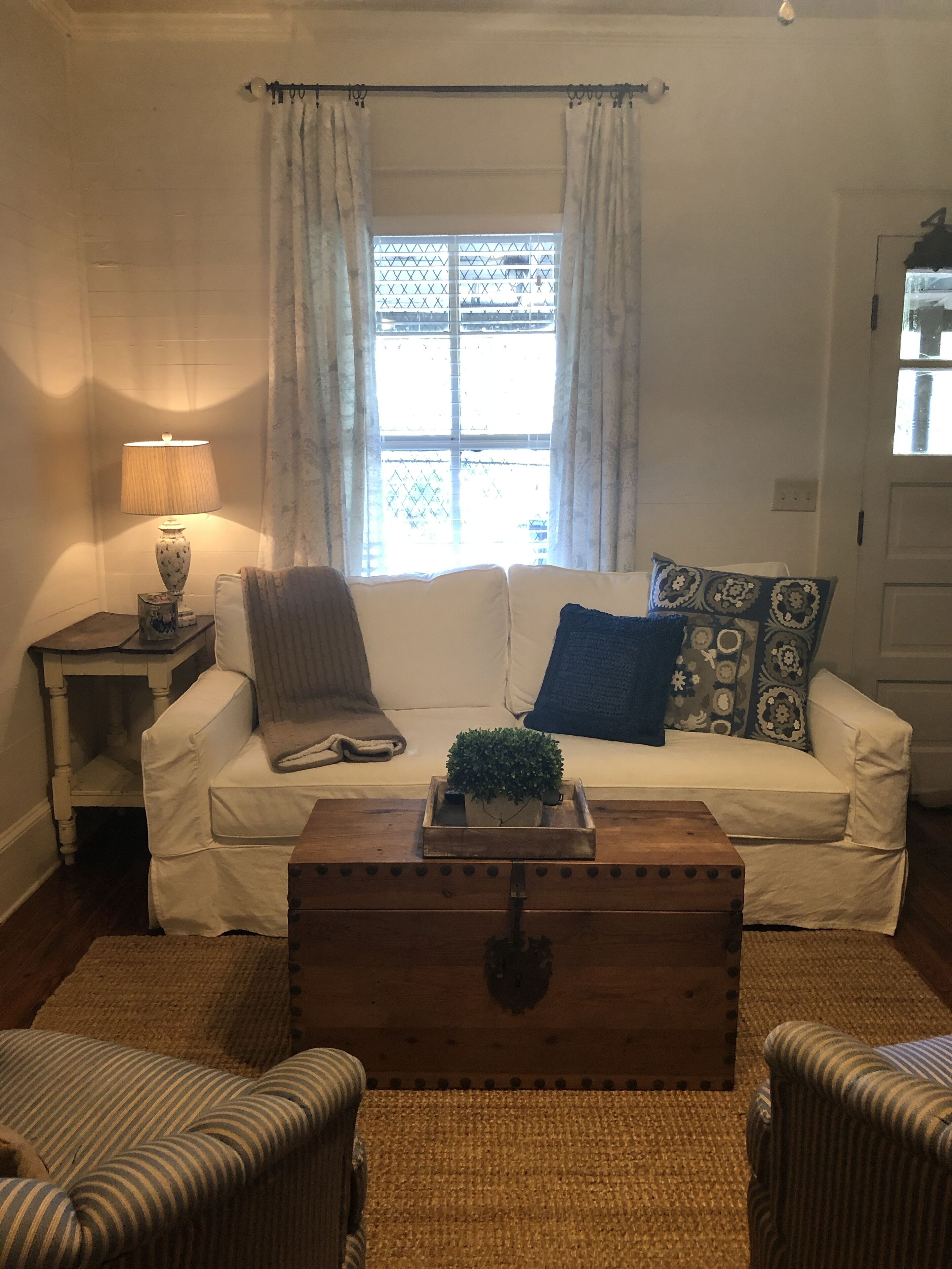 Un salon confortable avec un canapé, une table basse et une fenêtre avec des rideaux.