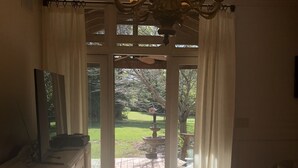 Une pièce faiblement éclairée, ornée d’un lustre, avec une fenêtre à rideaux et une table de baby-foot.
