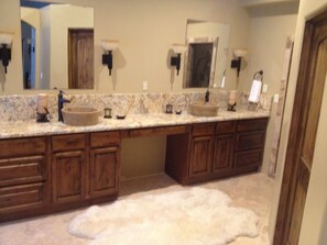 A bathroom with a double sink vanity, wooden cabinets, and a fluffy rug on the floor. - Your Mountain get away  (Durango)