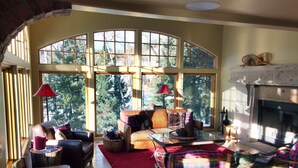 A cozy living room with a fireplace, large windows, and comfortable seating.