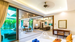 Habitación de hotel moderna con una cama grande, un escritorio y vistas a una piscina y zonas verdes.