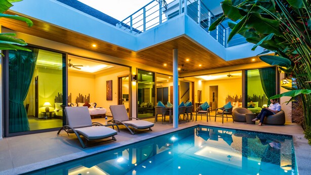 Un área de piscina moderna al aire libre con sillones de descanso y zona de comedor.