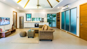 Una sala de estar moderna con un sofá, un reposapiés y una mesa de centro de vidrio.