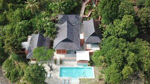 Vista aérea de uma casa com piscina, cercada por vegetação densa.