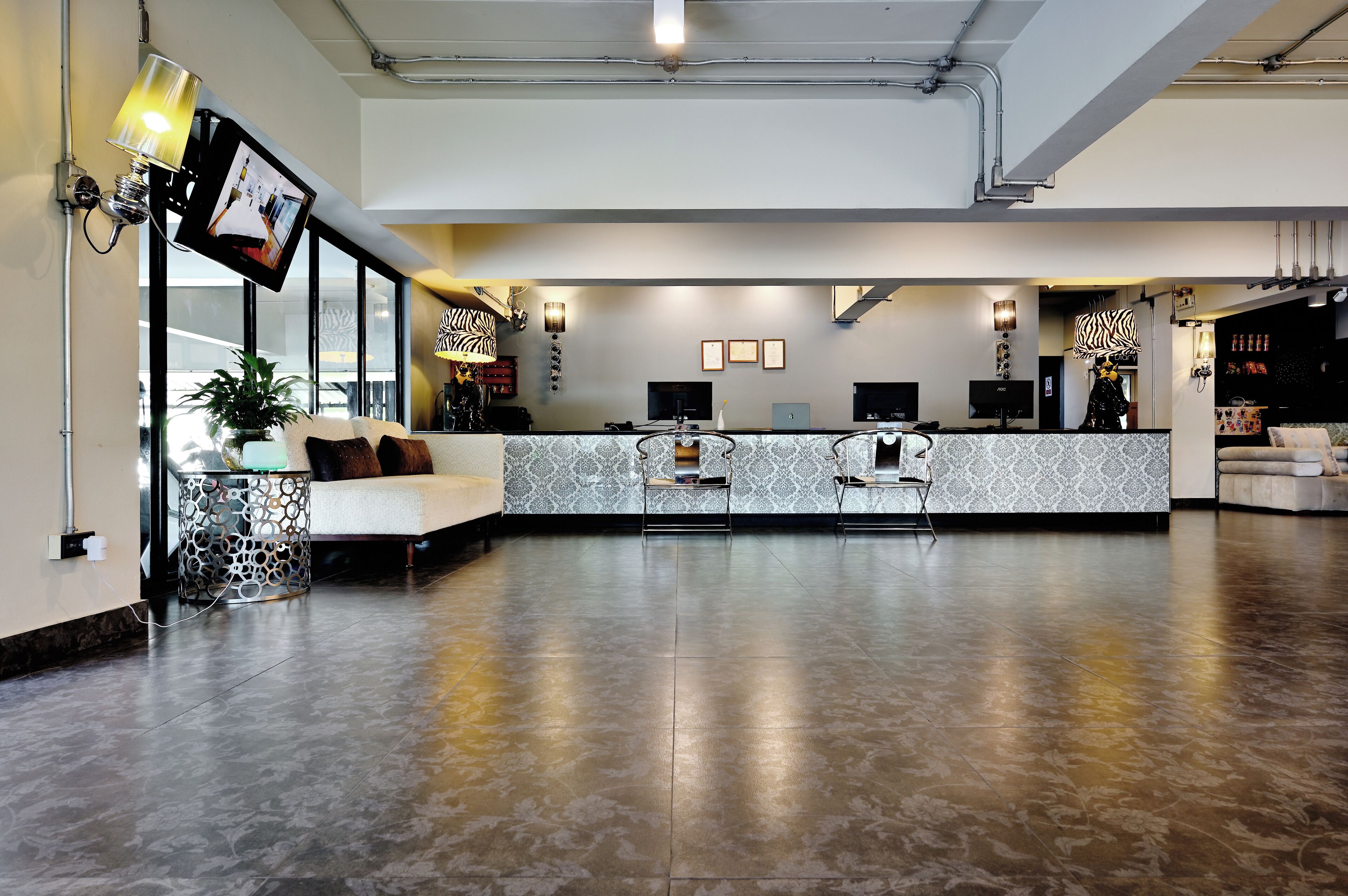 A spacious lobby with a reception desk, seating area, and a large plant.