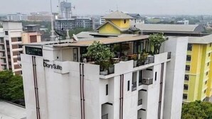 A multi-story building with balconies, a rooftop garden, and a visible satellite dish. - Diary Suite (Nakhon Pathom)