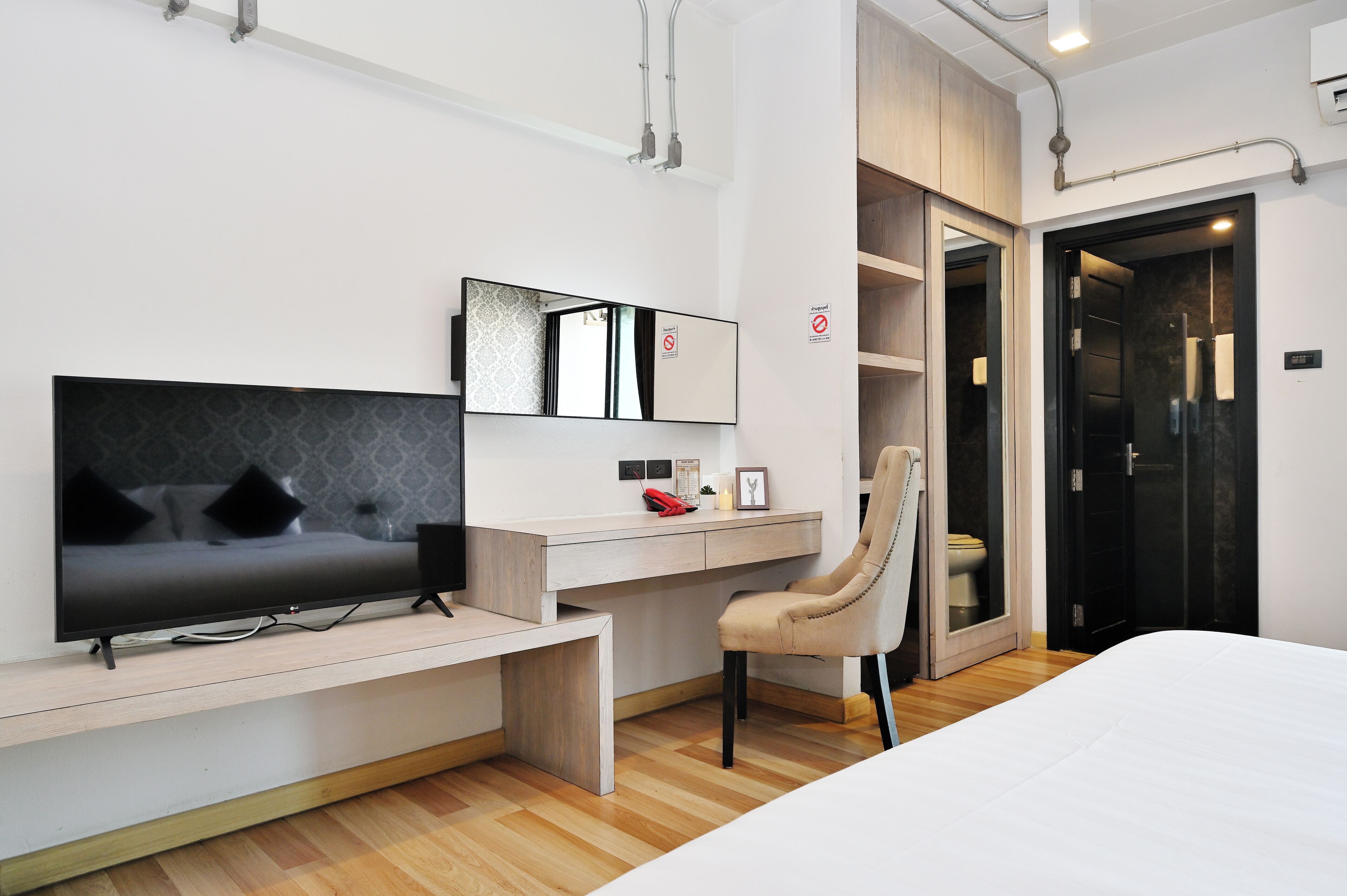 A modern bedroom with a TV, desk, chair, and bed.