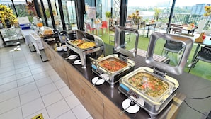 A buffet area with various food options, a coffee station, and a seating area with a view. - Diary Suite (Nakhon Pathom)