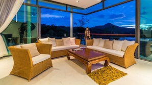 Un salón moderno con muebles de mimbre y grandes ventanales con vistas al exterior.