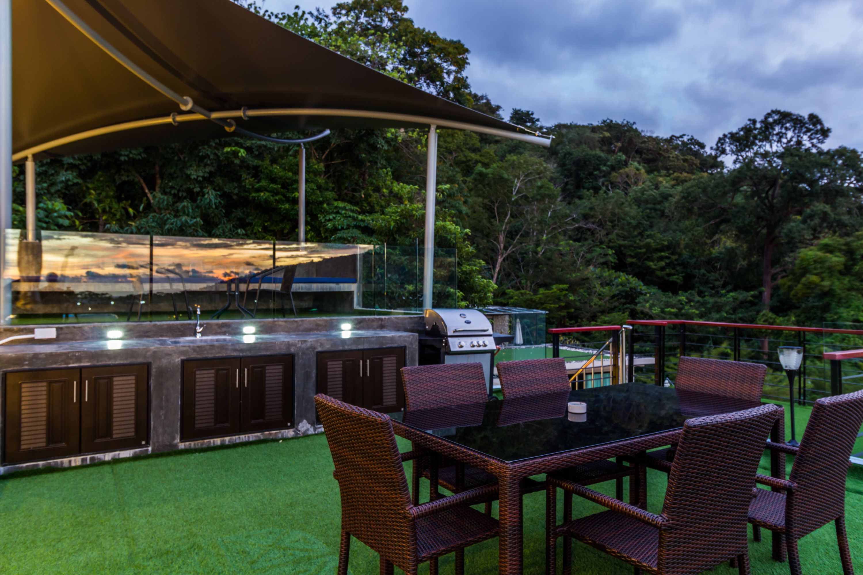 Un patio al aire libre con una parrilla, sillas de mimbre y una mesa.