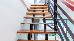 Una escalera moderna con escalones de madera y barandillas de metal negro.