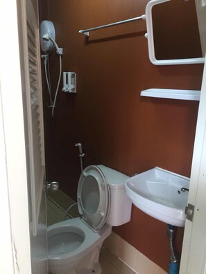 Un baño pequeño con inodoro, lavabo y secador de pelo fijado a la pared.