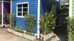 Una casa azul con un ventanal blanco y macetas de concreto con plantas.