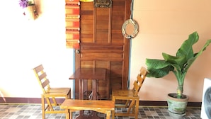 Una puerta de madera con un espejo decorativo, dos sillas de madera, una mesa y una planta en maceta.