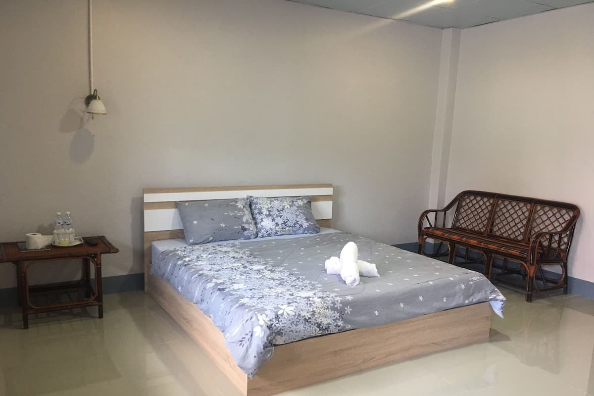 A neatly made bed with a floral bedspread, a wooden headboard, and a bedside table with toiletries.
