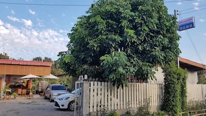 Un edificio con un cartel, una zona delimitada por una valla y coches aparcados.