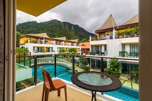 A hotel balcony with a pool, a dining table, and a chair.