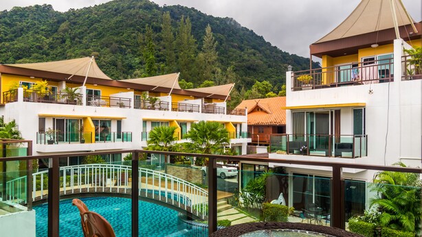 A hotel with a swimming pool, multiple balconies, and a view of a forested mountain. - AP Grand Residence by Lofty (Kamala)