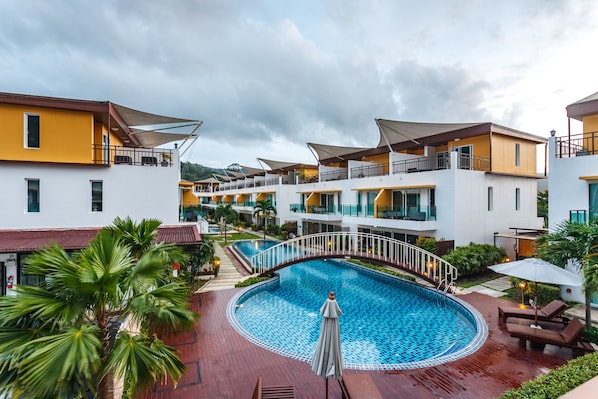 A hotel with a pool, multiple balconies, and a tropical garden.