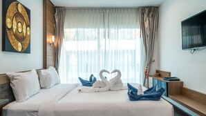 A hotel room with a large bed, a flat-screen TV, and a painting on the wall. - AP Grand Residence by Lofty (Kamala)