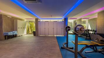 Un gimnasio moderno con equipo de ejercicio, piso acolchado y vistas al exterior con zonas verdes.