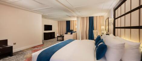 A hotel room with a large bed, a desk, a chair, and a TV.