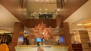 A modern lobby with a central water feature, a staircase, and a reception desk. - Blue Inn (Abha)