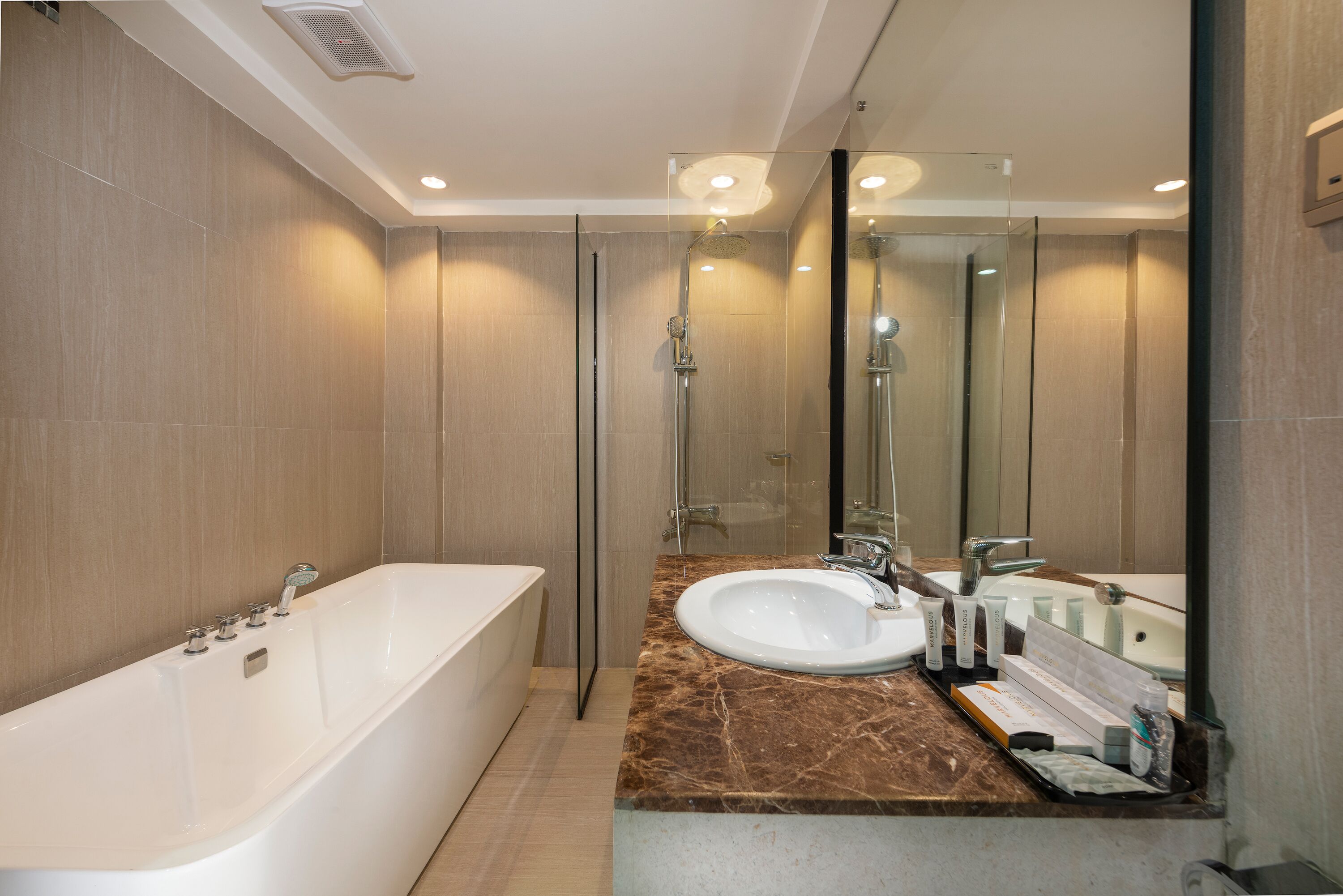 Un baño moderno con una bañera, un lavamanos y un espejo grande.