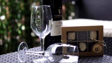 Una bottiglia di vino, un bicchiere e una scatola di cioccolatini su un tavolo con uno sfondo sfocato all'aperto.
