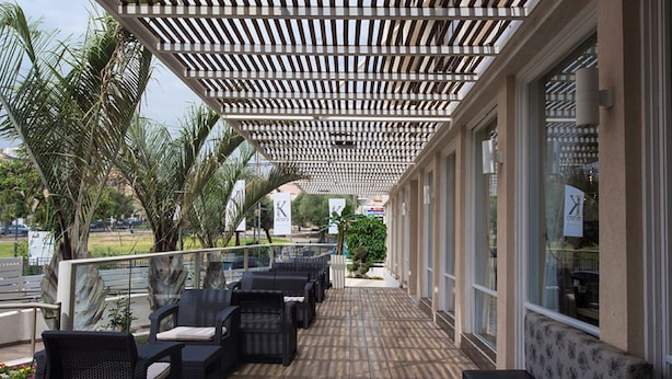 A covered outdoor seating area with wicker furniture and a wooden floor.