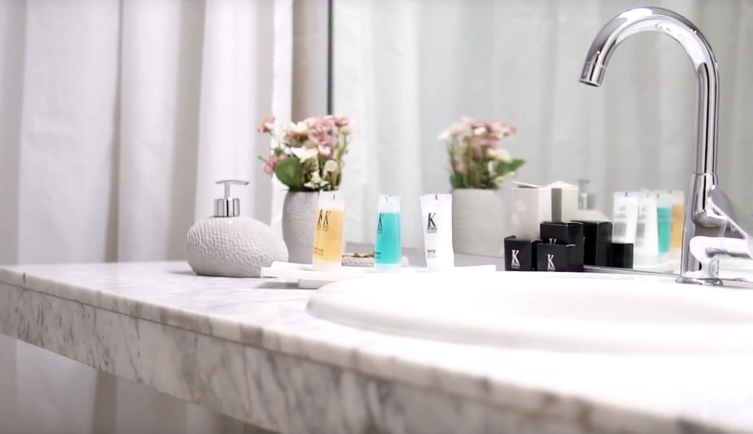 A bathroom with a marble countertop, a modern faucet, and various toiletries.