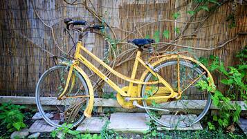 A yellow bicycle leaning against a bamboo fence.