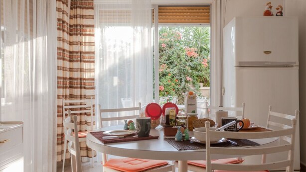 Un coin repas avec une table ronde, des chaises et une fenêtre avec des rideaux.
