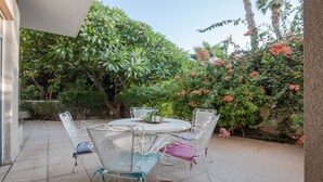Une terrasse extérieure avec une table ronde et quatre chaises.