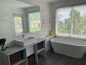 Une salle de bain moderne avec une baignoire sur pieds, un grand miroir et un meuble-lavabo.