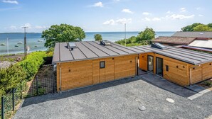 A wooden cabin with a sloped roof, a small porch, and a view of the sea.