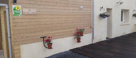 Eine Holzfassade mit Schild, Blumentöpfen und einer Metallleuchte.