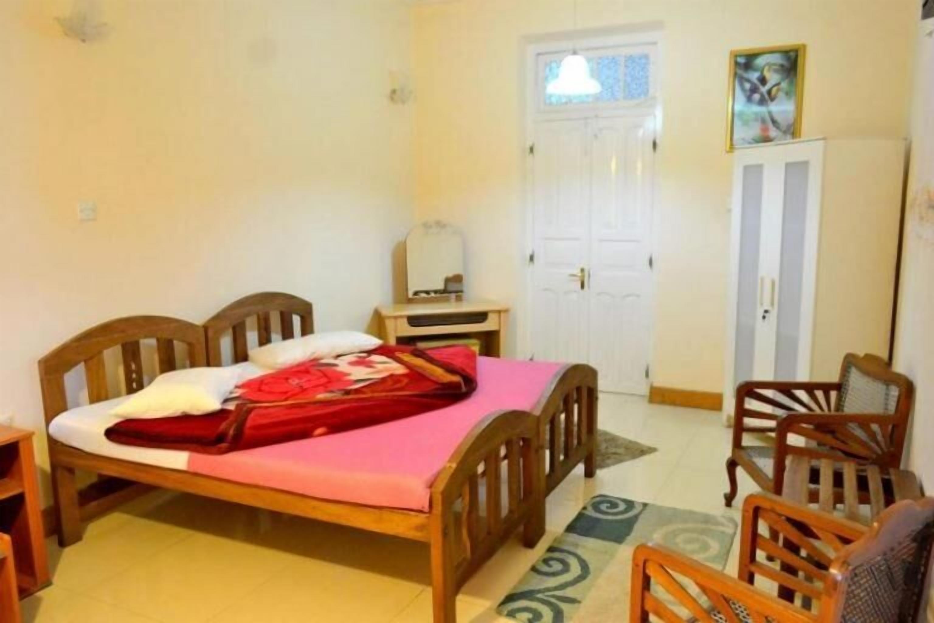 Een slaapkamer met een houten bed, een bureau, een stoel en een kledingkast.