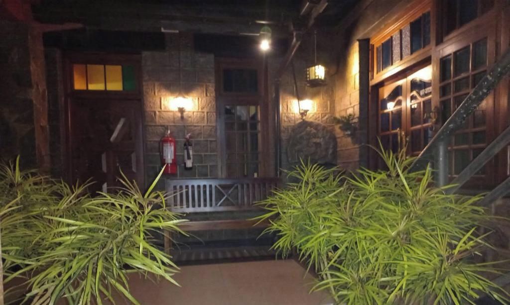 A stone building with a wooden staircase, a fire hydrant, and potted plants.