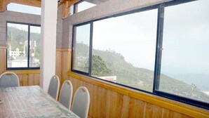 Un comedor con mesa y sillas, ventanas amplias con vistas a un paisaje montañoso.