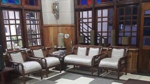 Una sala de estar con muebles de madera, una mesa de centro de vidrio y ventanas amplias con vidrieras.